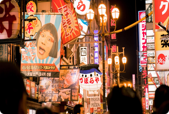 Neon shop signs on a busy street at night